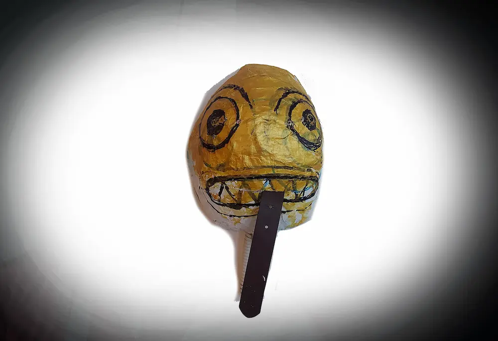 Proyecto de video arte experimental. Mascara de papel corrugado y pintada de dorado, con un retazo de correa marron saliendole de la boca como si fuera una lengua